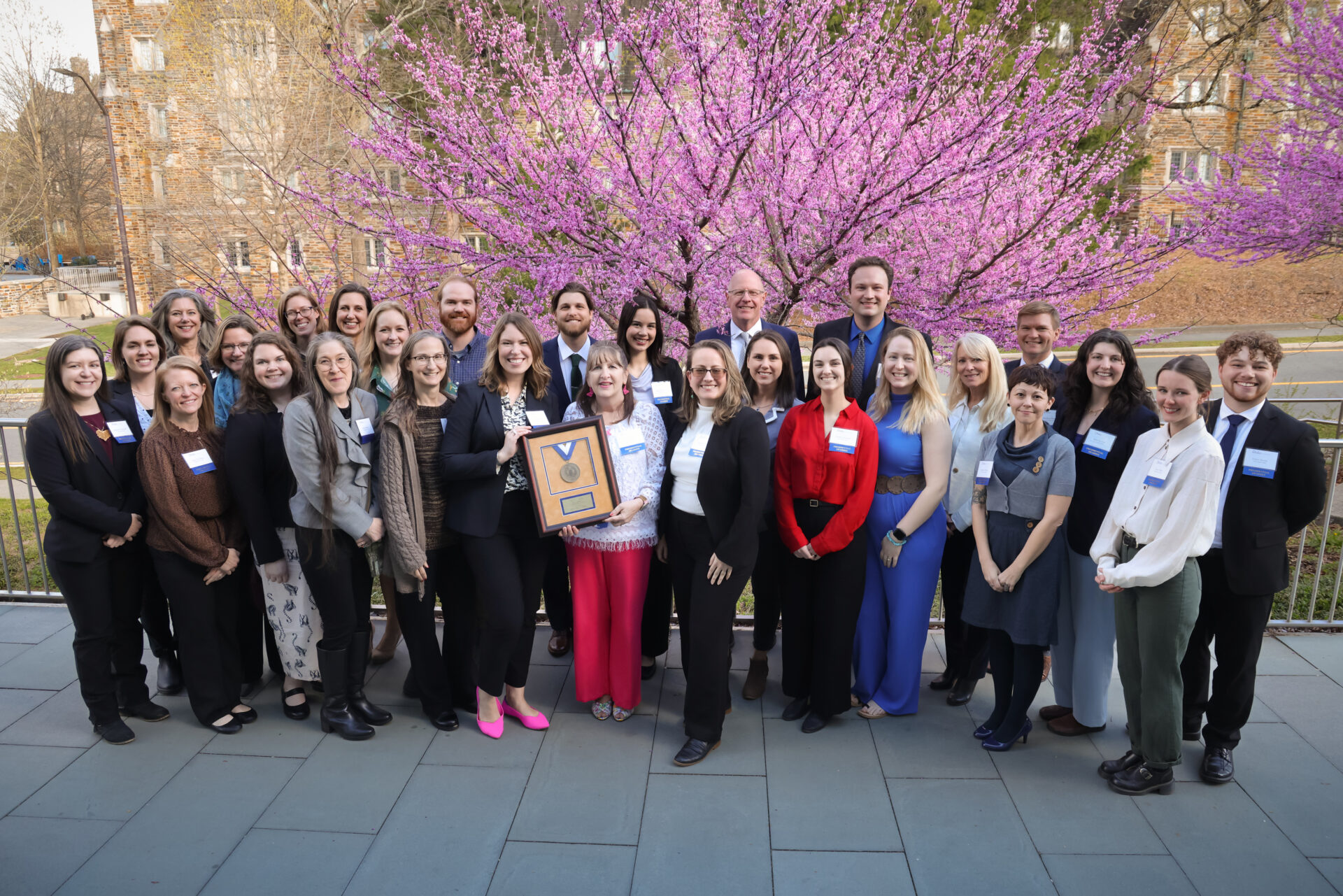 The Duke Lemur Center team stand outside near a blossoming cherry tree at the Awards Banquet