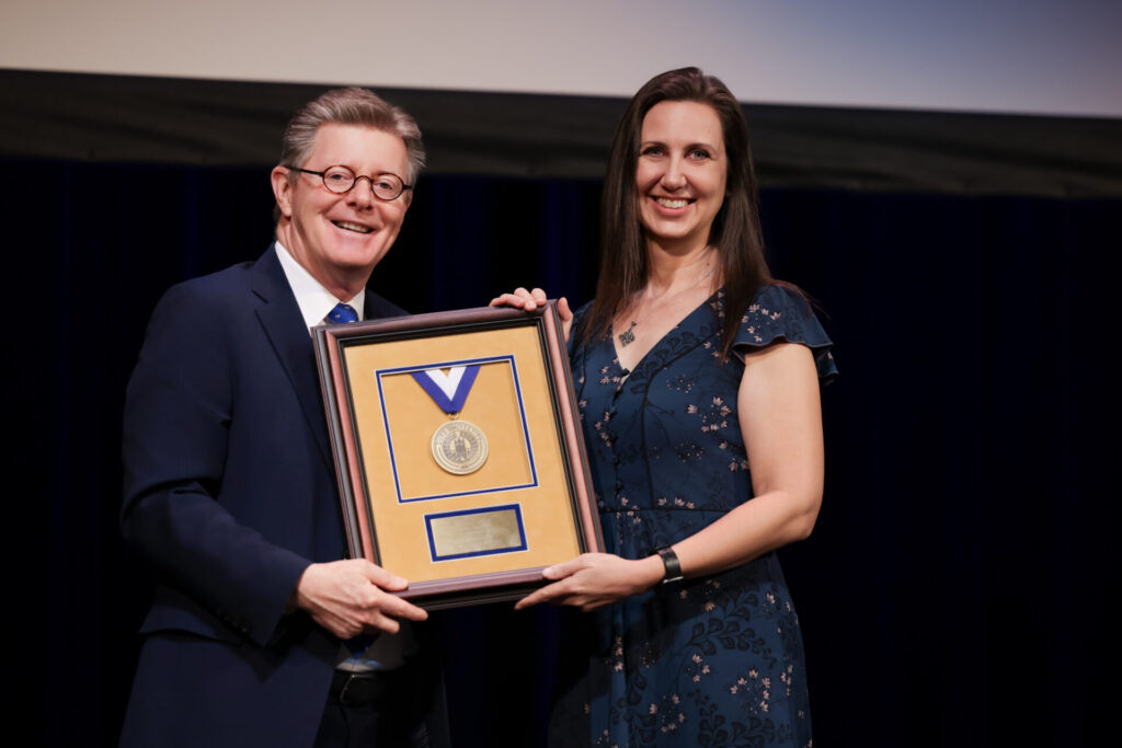 Duke University President Vincent Price presents the team's award to DLC Director of Research Erin Ehmke